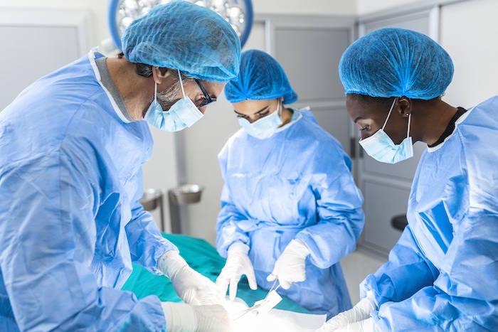 Group of surgeons doing surgery in hospital operating theater. Medical team doing critical operation. Group of surgeons in operating room with surgery equipment. Modern medical background